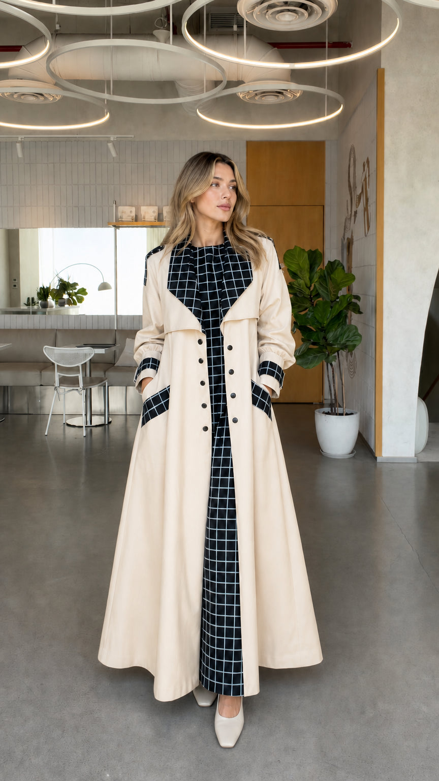 Full front view of model wearing beige cream maxi trench coat with black grid contrast trim