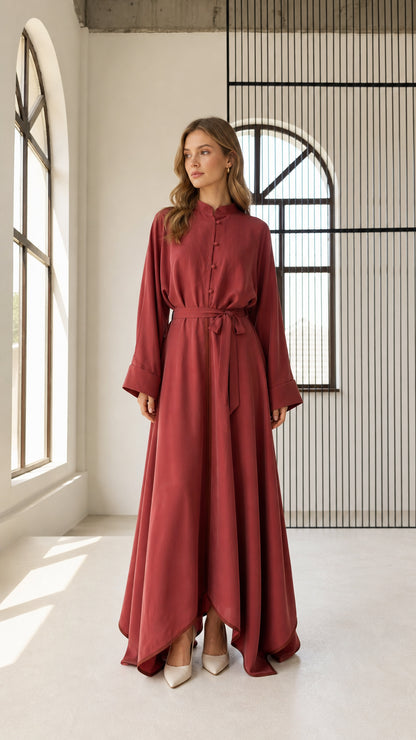 Front full view of woman wearing rust red long sleeve belted flowy maxi dress with stand collar