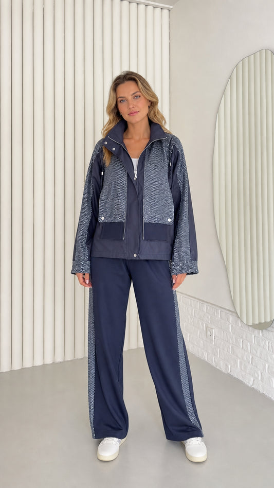Front full view of woman wearing navy blue textured contrast zip-up jacket and wide-leg pants set