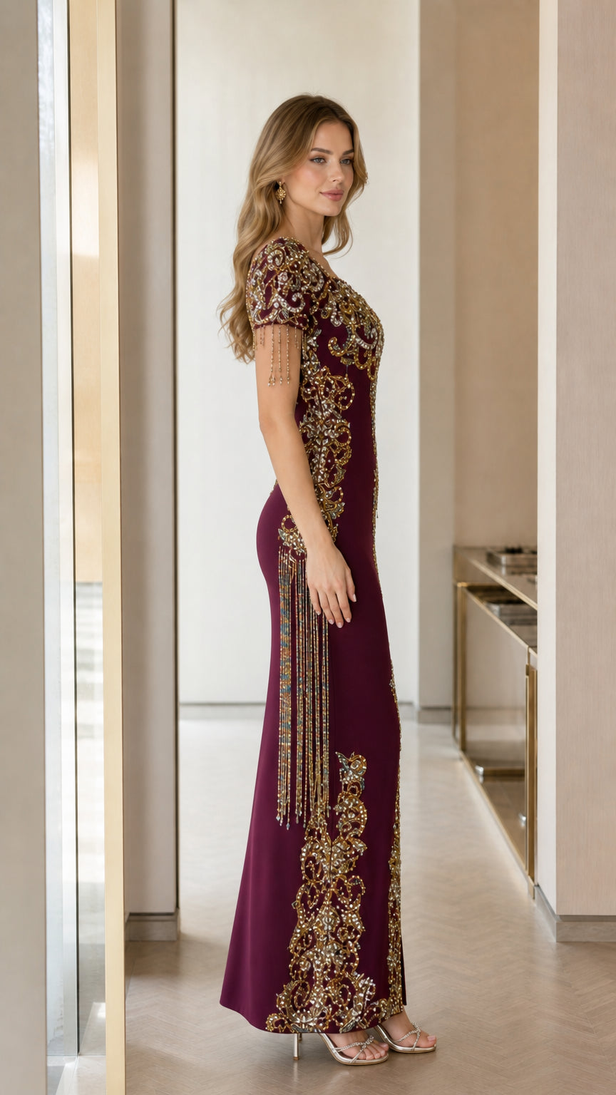 Side profile view of burgundy beaded maxi dress showcasing fitted silhouette and sleeve fringe