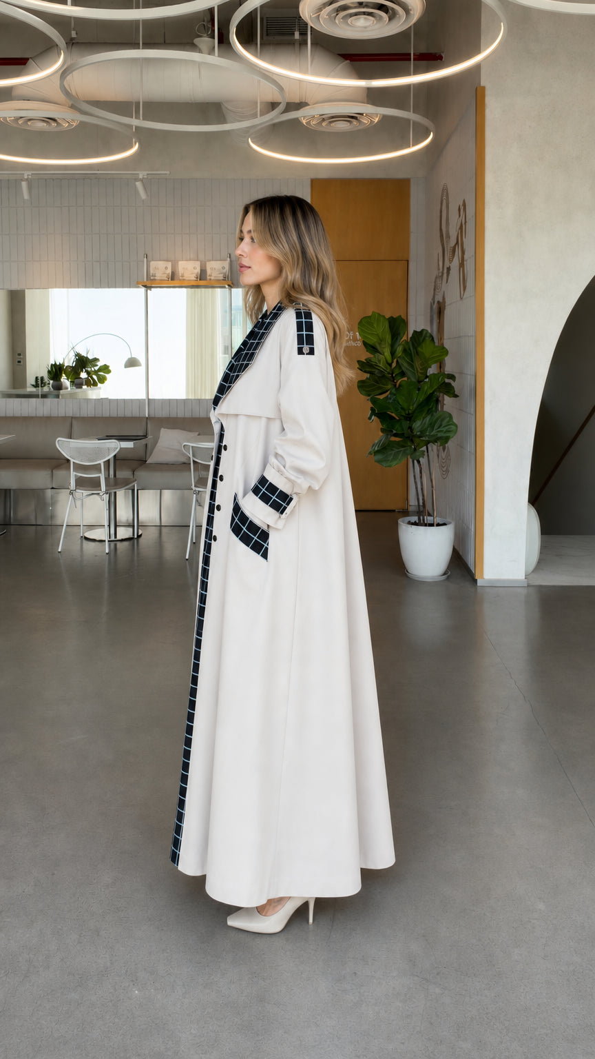 Side angle view of model wearing off white maxi longline duster coat with grid plaid trim