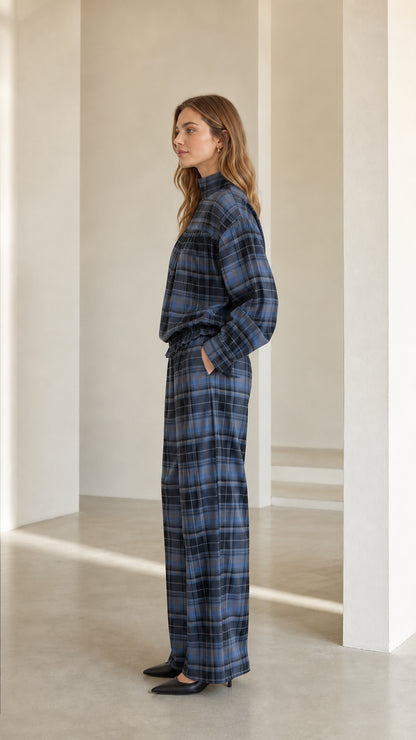 Side profile view of model in relaxed blue plaid blouse and wide leg matching pants