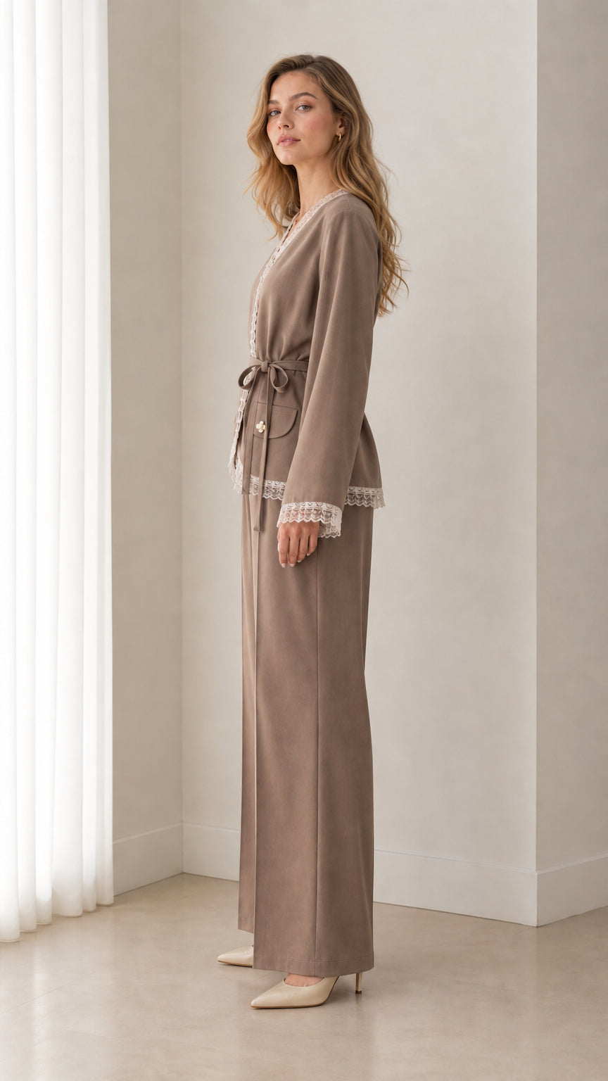 Side profile view of woman wearing taupe wrap suit set with tie belt