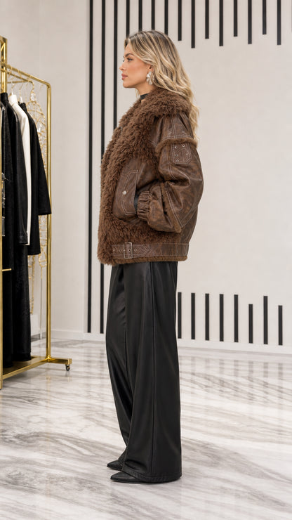 Side profile view of woman wearing brown textured faux shearling and leather jacket