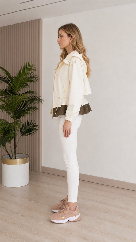 Side profile view of model wearing cream lightweight hooded utility jacket with white jeans