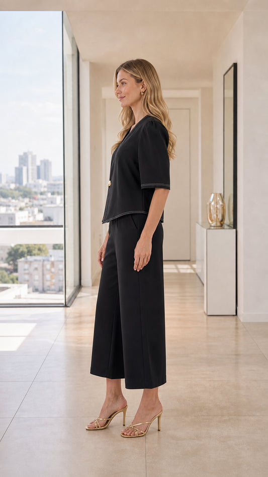 Side profile of black tailored two-piece set featuring asymmetric top and wide-leg trousers