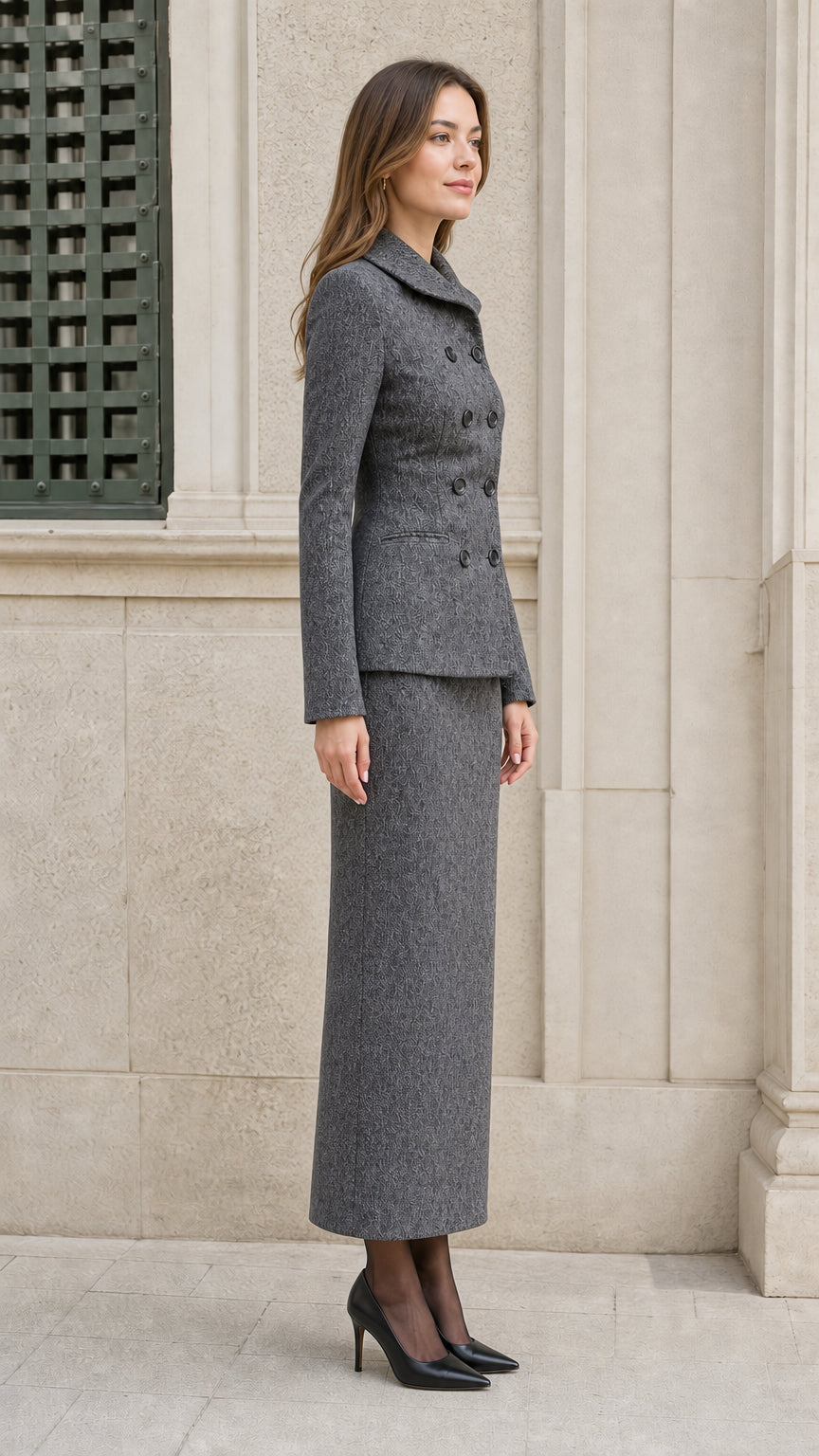 Side profile view of woman wearing Heather Grey tailored blazer and long skirt suit