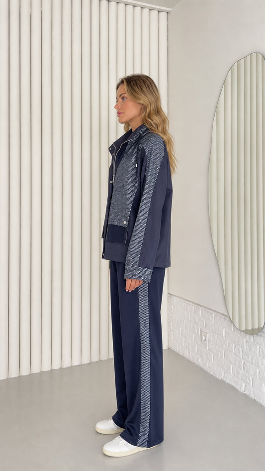 Side profile view of woman wearing navy blue two-piece jacket and wide-leg tracksuit