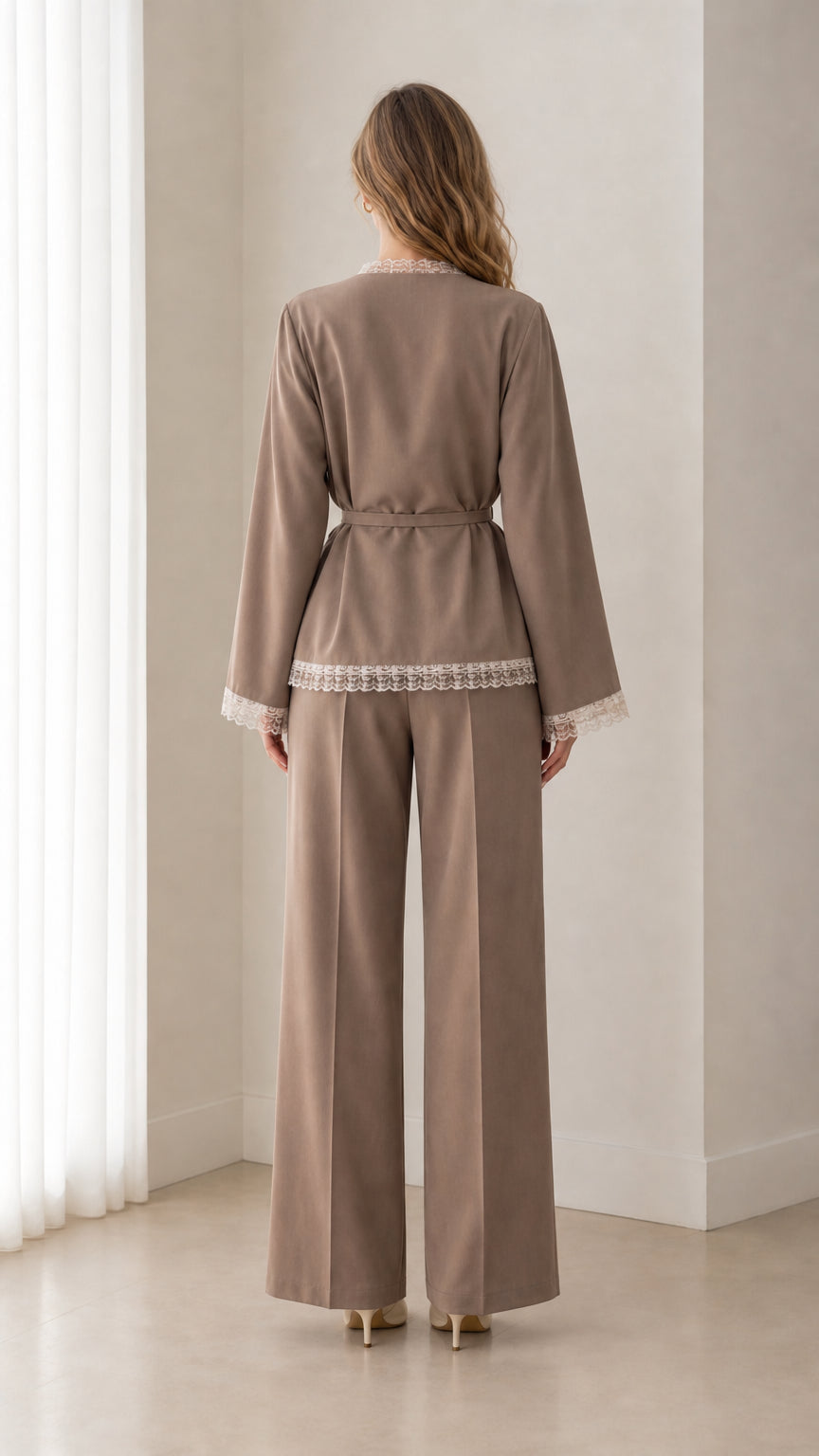Back view of woman wearing taupe lace-trimmed blazer and pleated wide-leg trousers