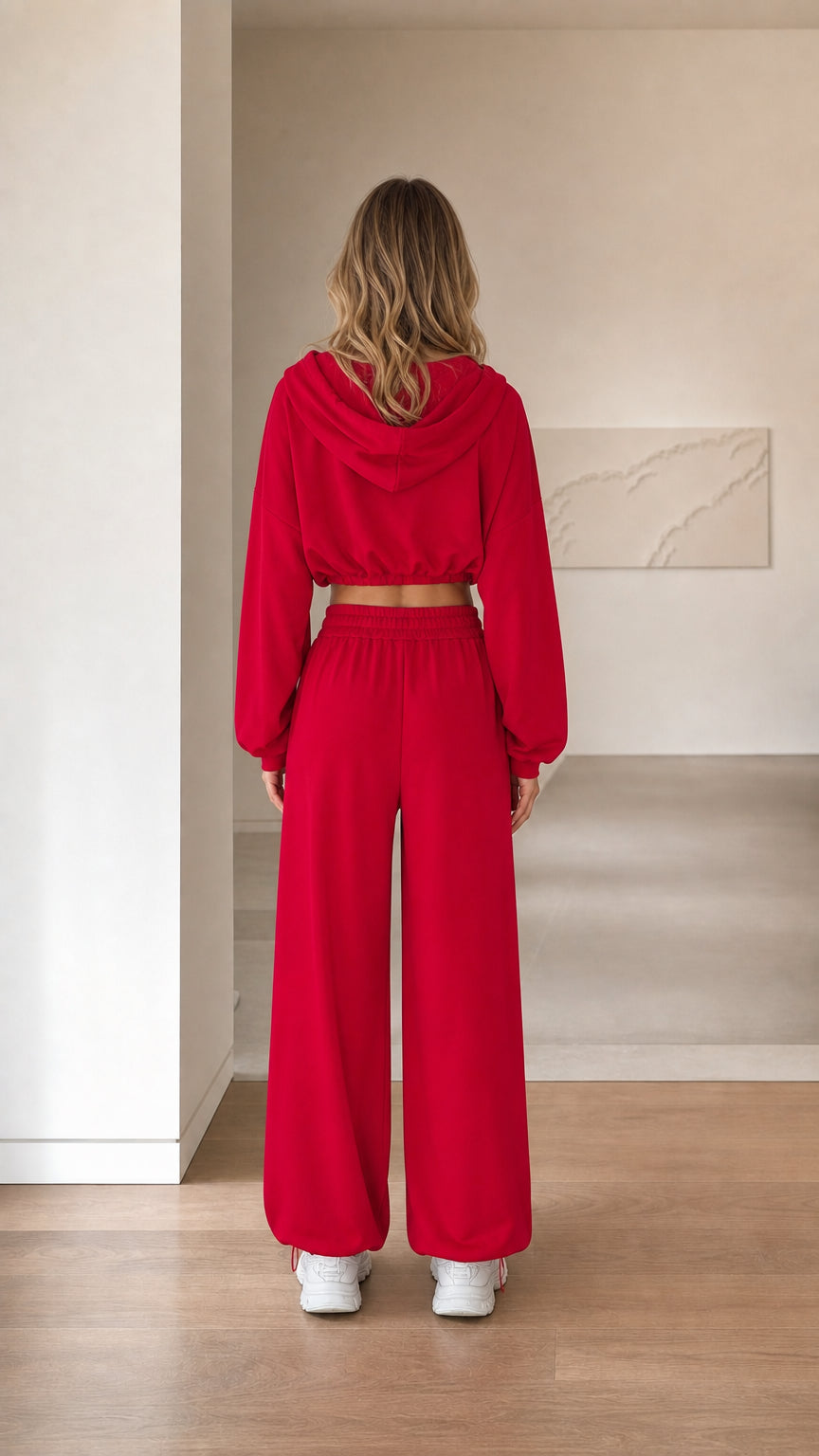 Back view of woman wearing red hooded cropped jacket and wide leg sweatpants