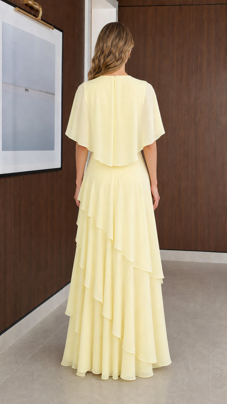 Back view of model wearing Pale Yellow chiffon maxi gown with capelet detail