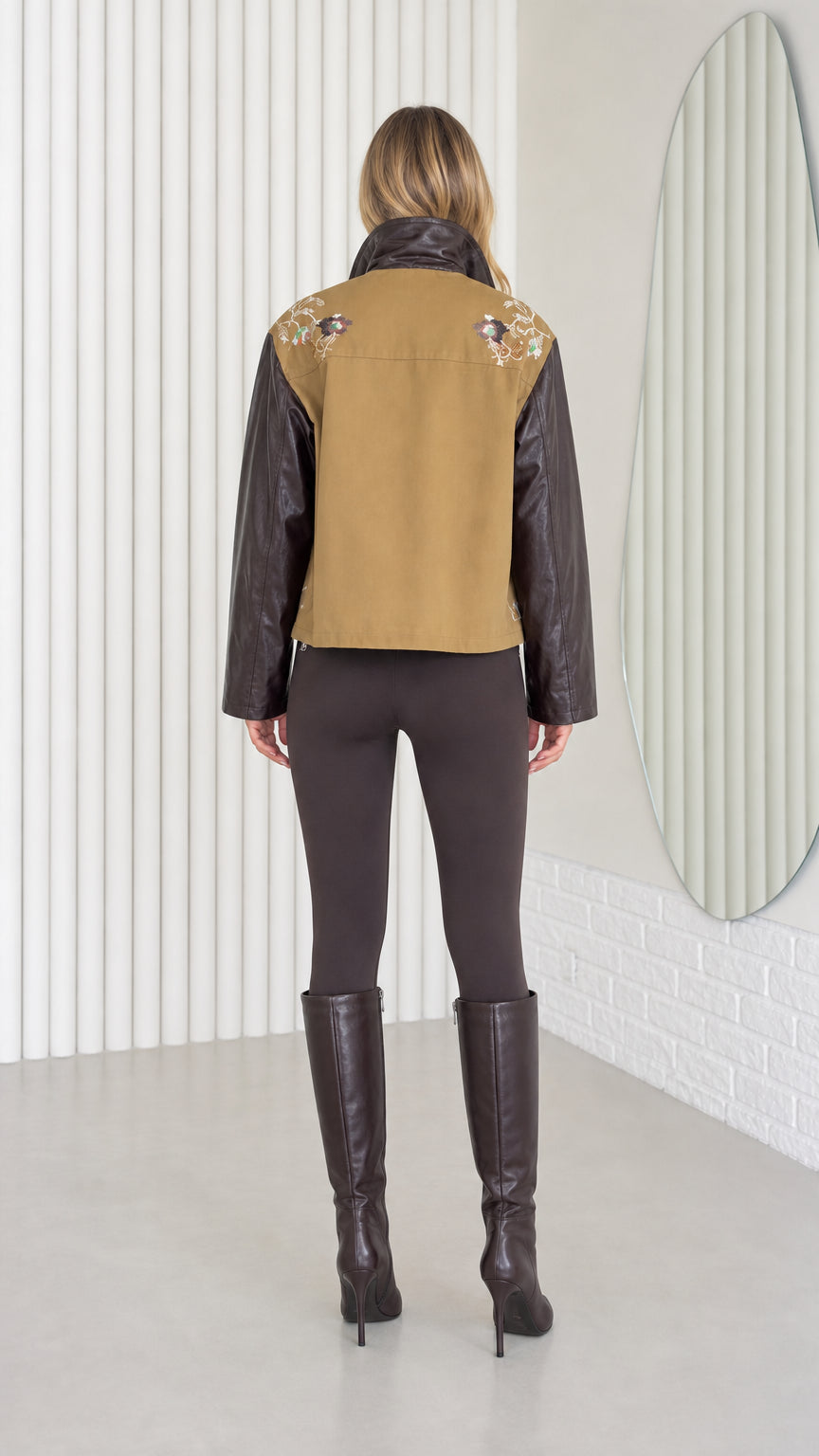 Model wearing Khaki embroidered jacket with faux leather sleeves, back view