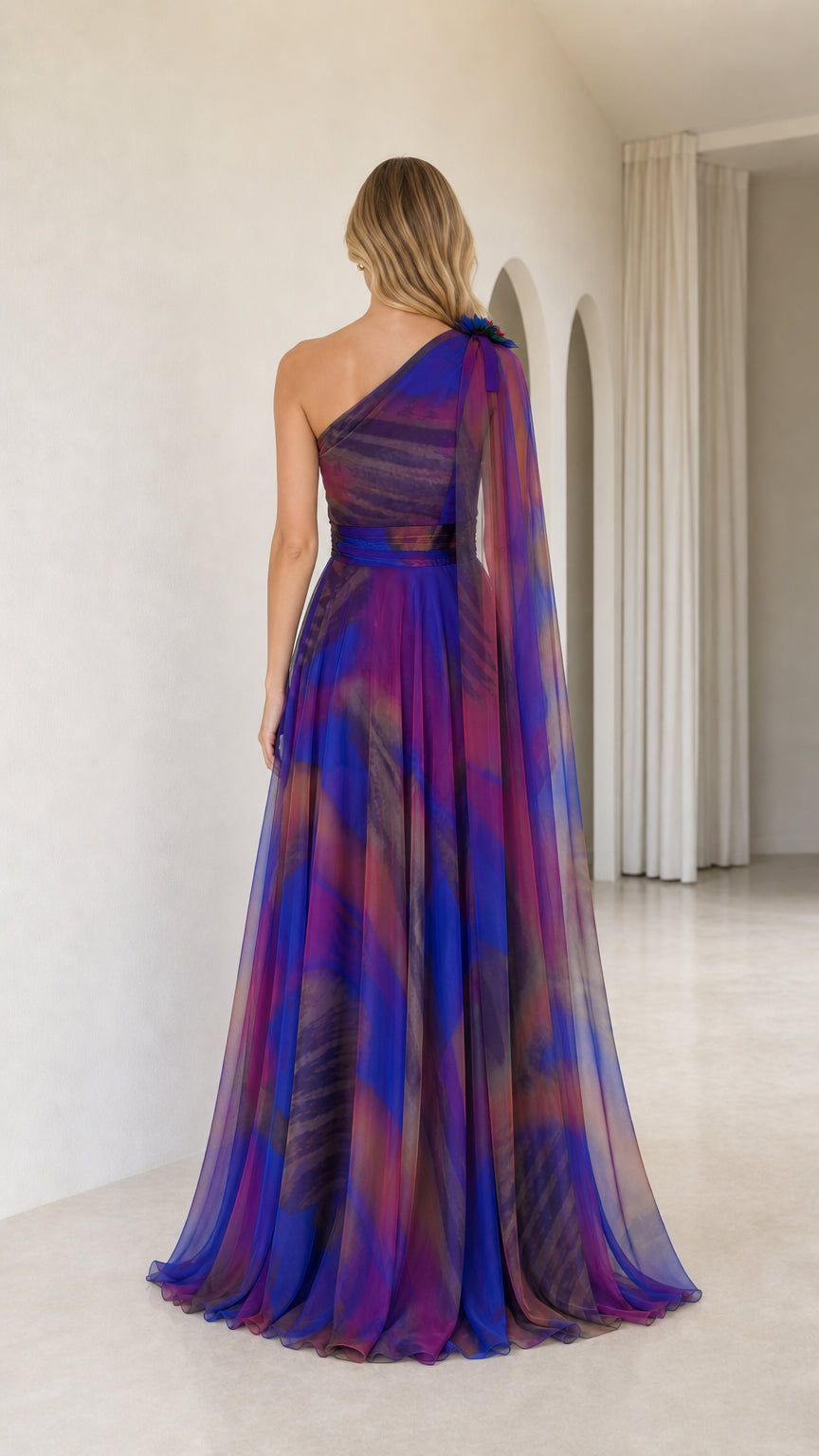 Back view of royal blue one-shoulder maxi dress with draped sheer chiffon cape