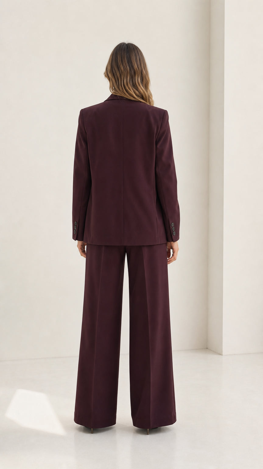 Back view of woman wearing tailored burgundy blazer and wide-leg trousers