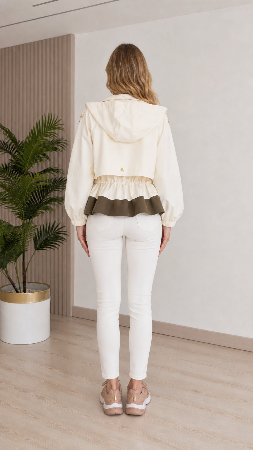 Back view of model wearing cream hooded windbreaker jacket showing cinched waist detail