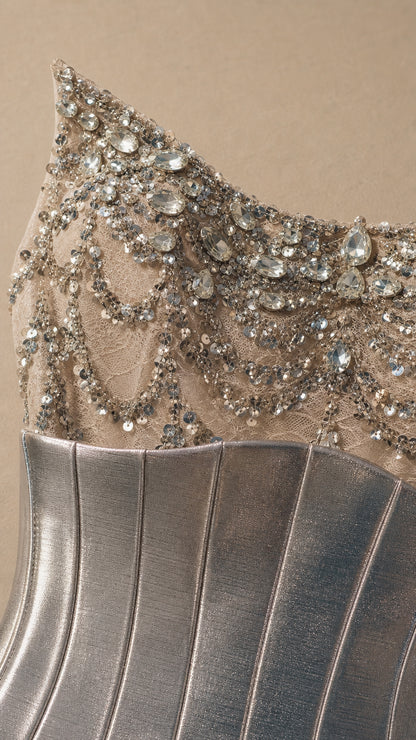 Close-up detail of silver crystal embellishments, beaded mesh, and metallic corset panel