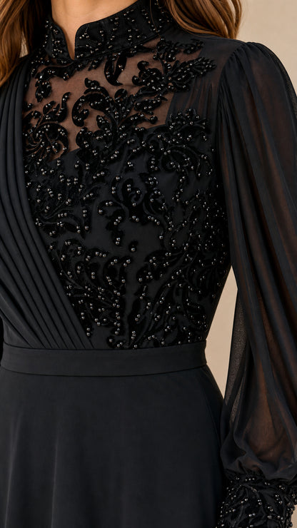 Close-up detail of beaded sheer neckline and pleated bodice on black evening gown