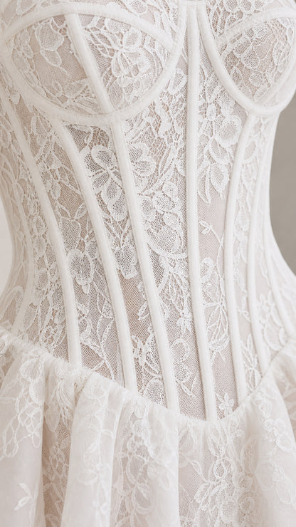 Close-up detail of white floral lace texture, cups, and corset boning