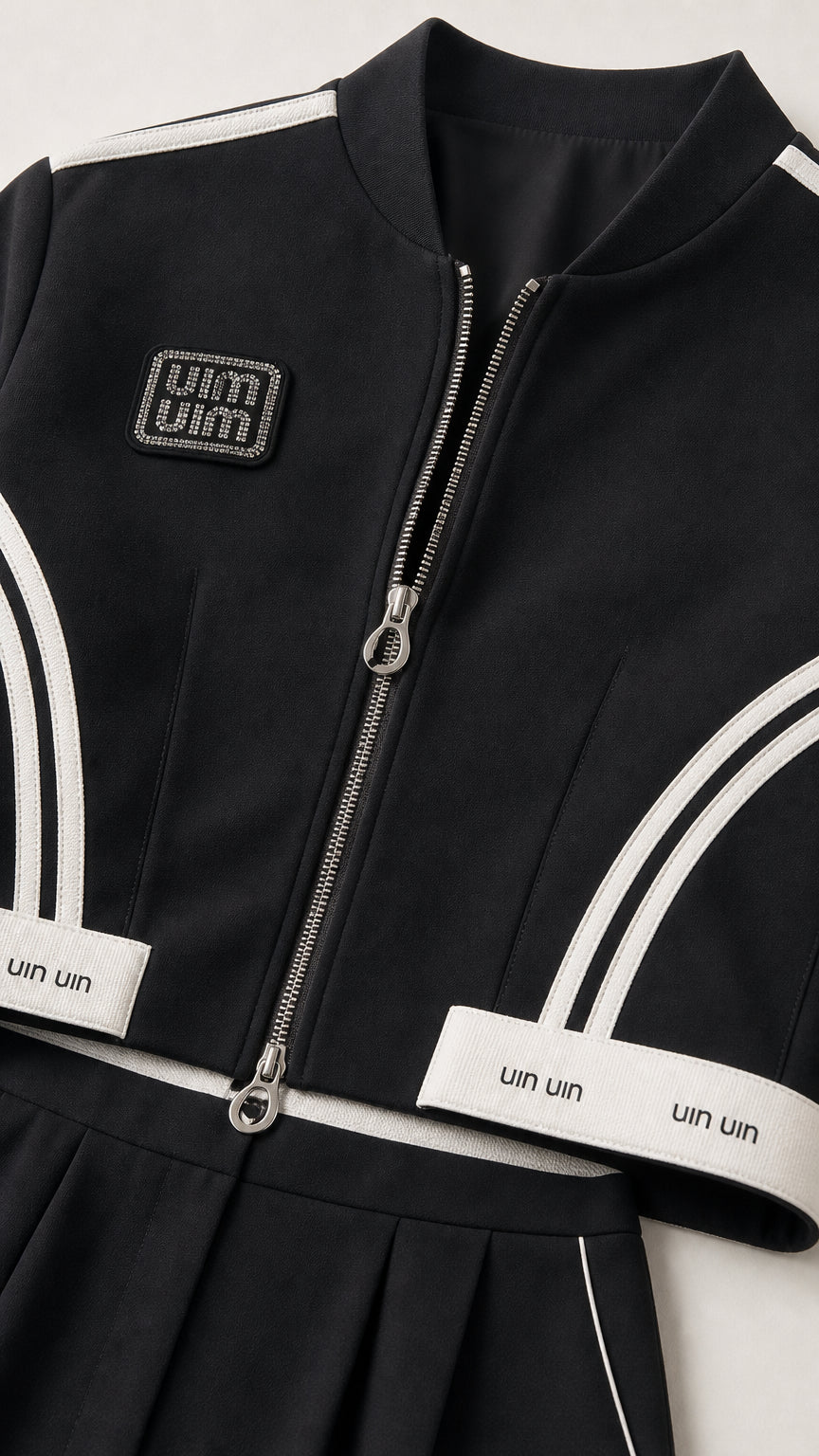Close-up detail of black cropped jacket showing double-end zipper and contrast trim