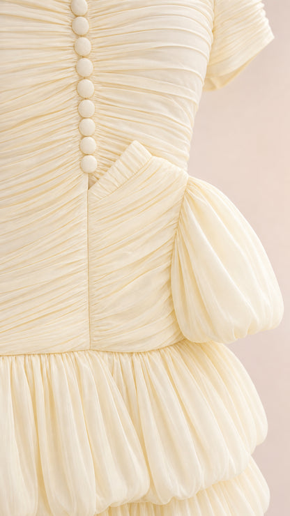 Close-up detail of cream ruched bodice with covered buttons and tiered ruffle