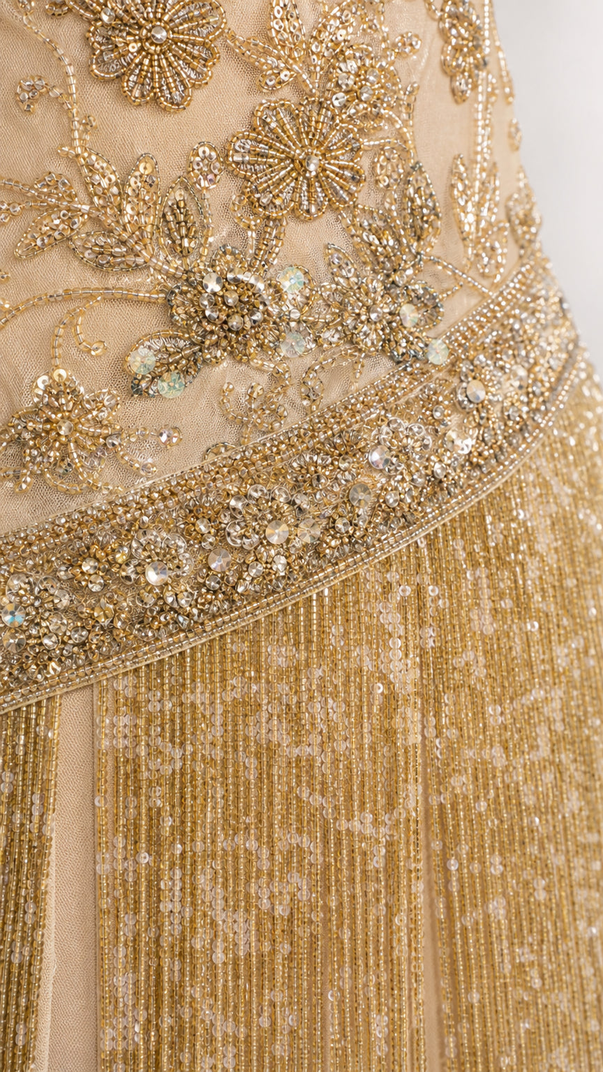 Close-up detail of gold floral beadwork, sequins, and layered fringe