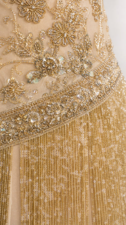 Close-up detail of gold floral beadwork, sequins, and layered fringe
