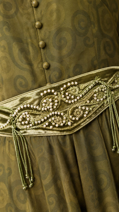 Close-up detail of green jacquard fabric, button front, and beaded waist embellishment