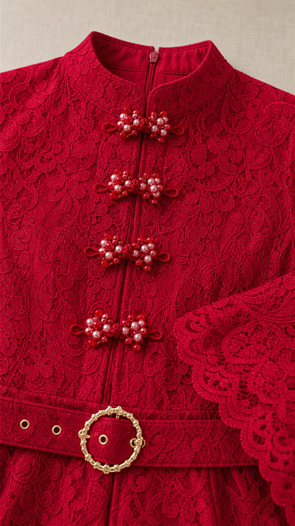 Close-up detail of red floral lace dress showing beaded frog buttons and round belt buckle