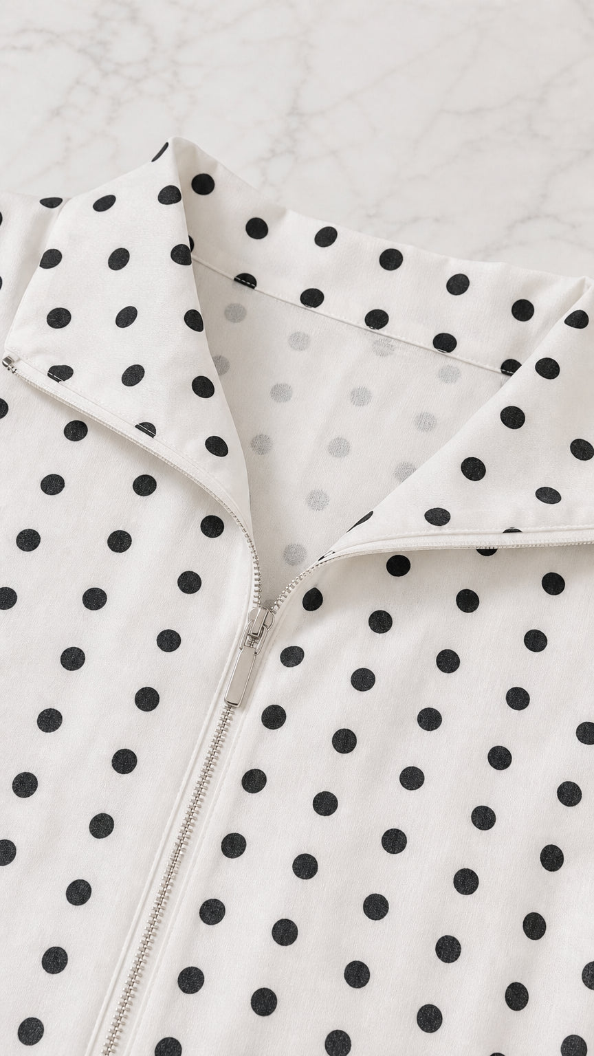 Close-up detail of the spread collar and front zipper on the polka dot top