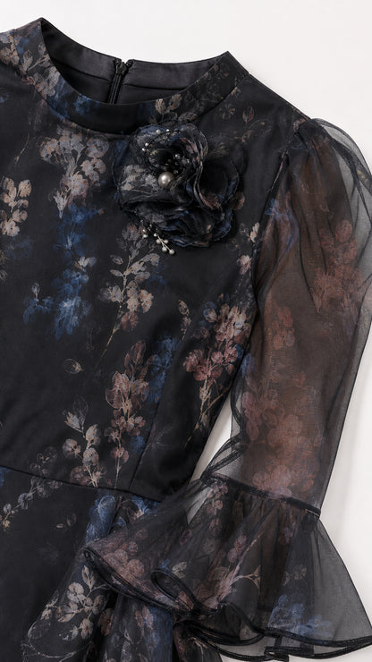 Close-up detail of neckline, 3D floral corsage, and sheer flared cuff on black floral dress