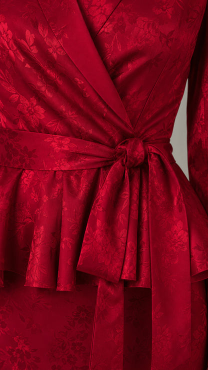 Close-up detail of floral jacquard fabric and waist tie on red peplum dress