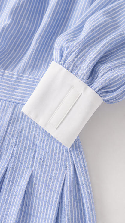 Close-up detail of light blue striped fabric and crisp white cuff sleeve
