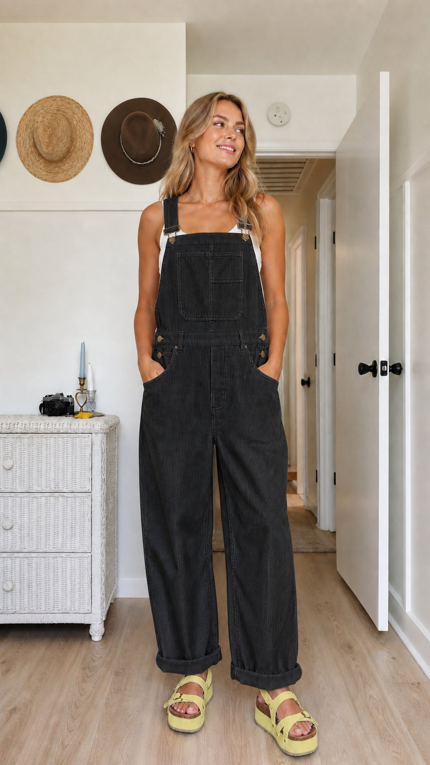 Model wearing black wide-leg bib overalls with a white top and adjustable straps