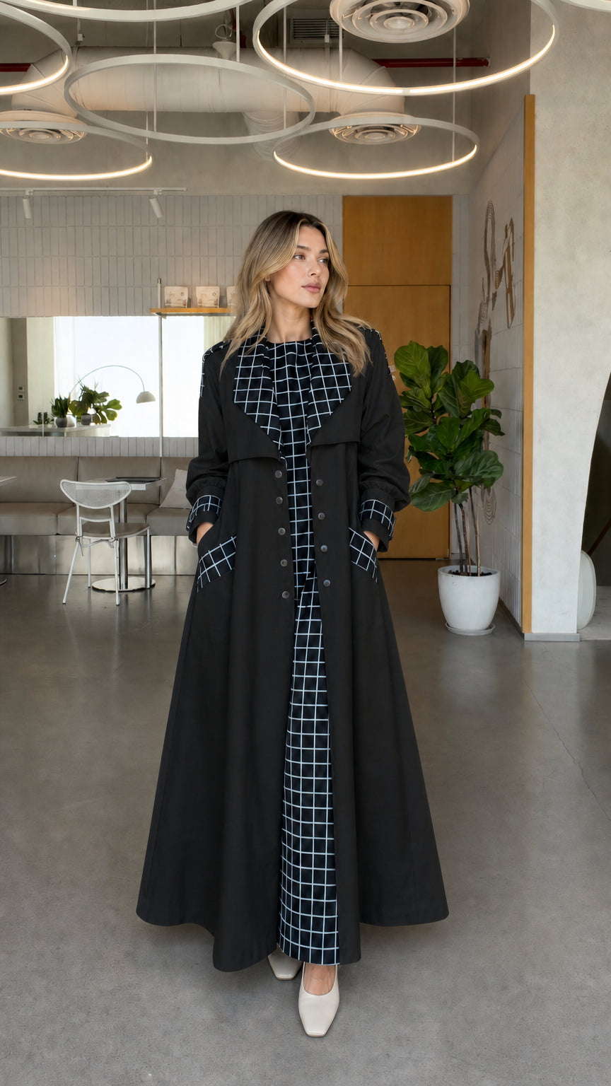 Full front view of model wearing black maxi trench coat with contrast windowpane grid trim