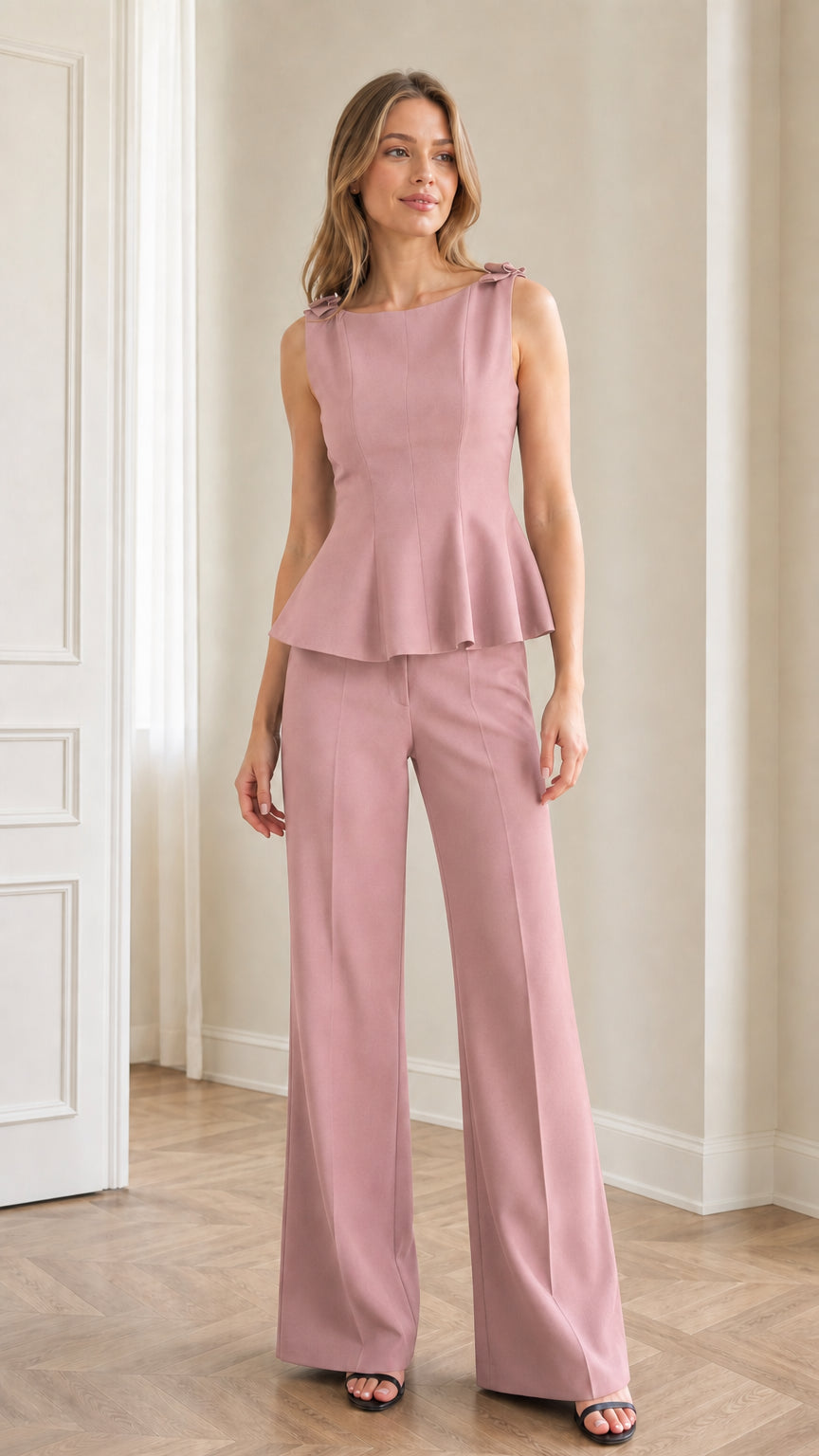 Model wearing dusty pink sleeveless bow-accent peplum top and wide-leg trousers set