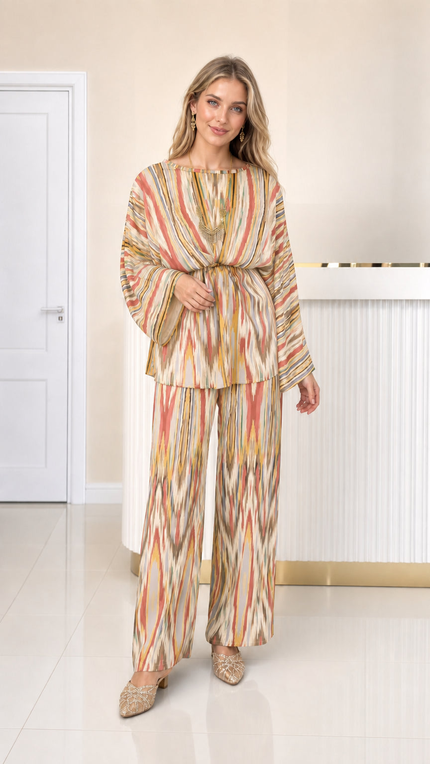 Front full view of woman wearing beige and warm yellow printed pleated pant set