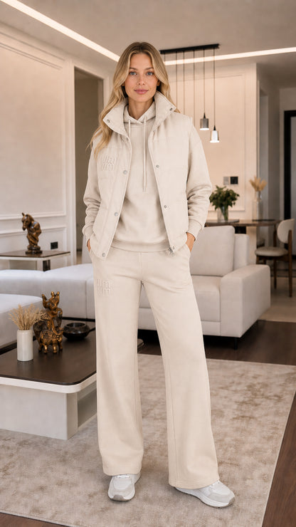 Model wearing cream off-white 3-piece puffer vest, hoodie, and wide-leg sweatpants set