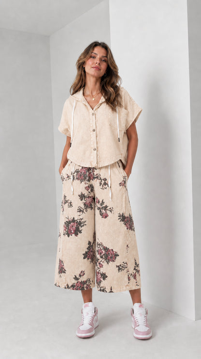 Front view of woman wearing washed beige hooded shirt and floral wide-leg pants set