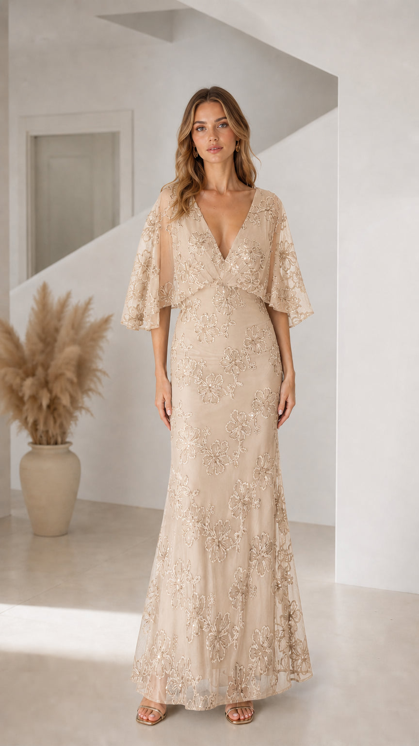 Front view of woman wearing champagne beige floral sequin flutter sleeve evening gown